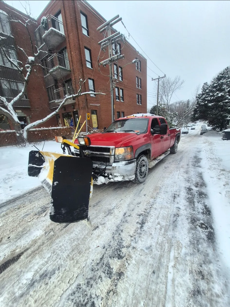 Camion de déneigement équipé d’une lame dans une rue résidentielle
